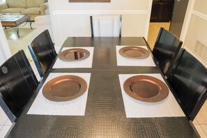 Una mesa de comedor con cuatro sillas, cada una con un plato marrón sobre un mantel individual.