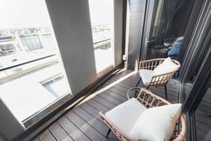 A balcony with wicker chairs and a view of the cityscape.