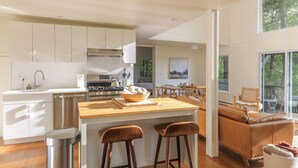 A modern kitchen with a central island, stainless steel appliances, and a dining area with a view. - Dreamy Catskills mountain getaway w/ yoga studio (Parksville)