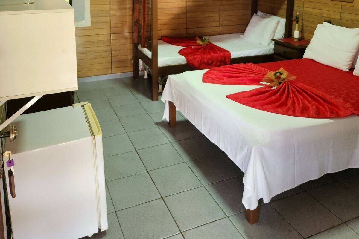 Habitación de hotel con literas, escritorio, refrigerador y piso de baldosas.