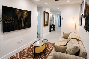 A modern living room with a sofa, a coffee table, and a large TV displaying 'House of the Dragon'. - Luxury New 4BR/4BA Executive Home-Sleeps 8  Workspace-Backyard-Parking (Miami)