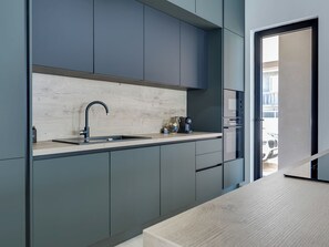 Eine moderne Küche mit Spüle, einer Kaffeemaschine und Blick ins Freie.