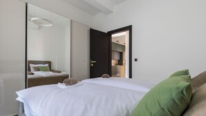 A hotel room with a bed, a mirror, a wardrobe, and a door leading to a kitchen area. - Fortunata by Interhome (Zadar/Bibinje)