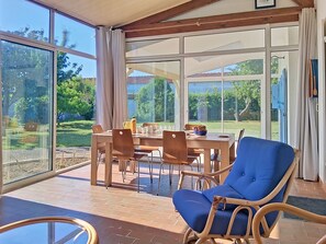 A dining area with a table, chairs, and a blue cushioned chair. - Les Tamarix by Interhome (Ile d'Oléron)