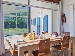 A dining area with a large table, chairs, and a view of the outdoors. - Les Tamarix by Interhome (Ile d'Oléron)
