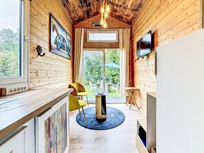 Ein gemütliches Blockhaus-Interieur mit Holzwänden, einer Essecke, einem Fernseher und einem großen Fenster.