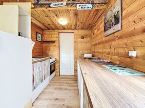 Ein Holzinnenraum mit Küchenbereich, einer Tür mit der Aufschrift 'Plage de Penvins' und einem Schild 'Sarzeau'.