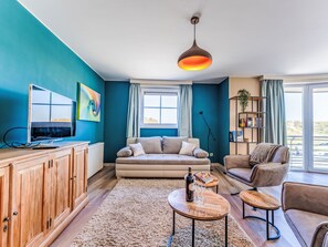 A modern living room with a sofa, two armchairs, a coffee table, a TV, and a bookshelf. - Breduynia 0401 with parking by Interhome (Bredene)
