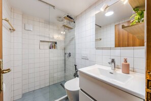 A modern bathroom with a glass shower enclosure, a white sink, and a mirror above it. - Villa Dita Qerret Relaxing Beachfront Stay (Golem)