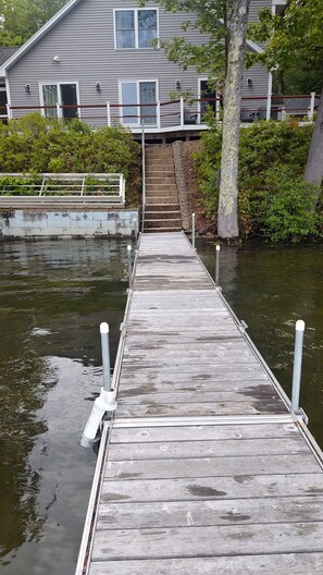 Un muelle de madera que lleva a una casa con una escalera de piedra.