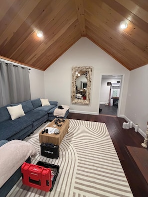 A loft-style room with a sloped ceiling, a blue sofa, a wooden coffee table, and a patterned rug.