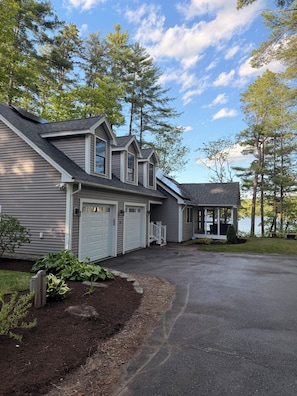 A two-story house with a garage, a covered porch, and a view of a lake.