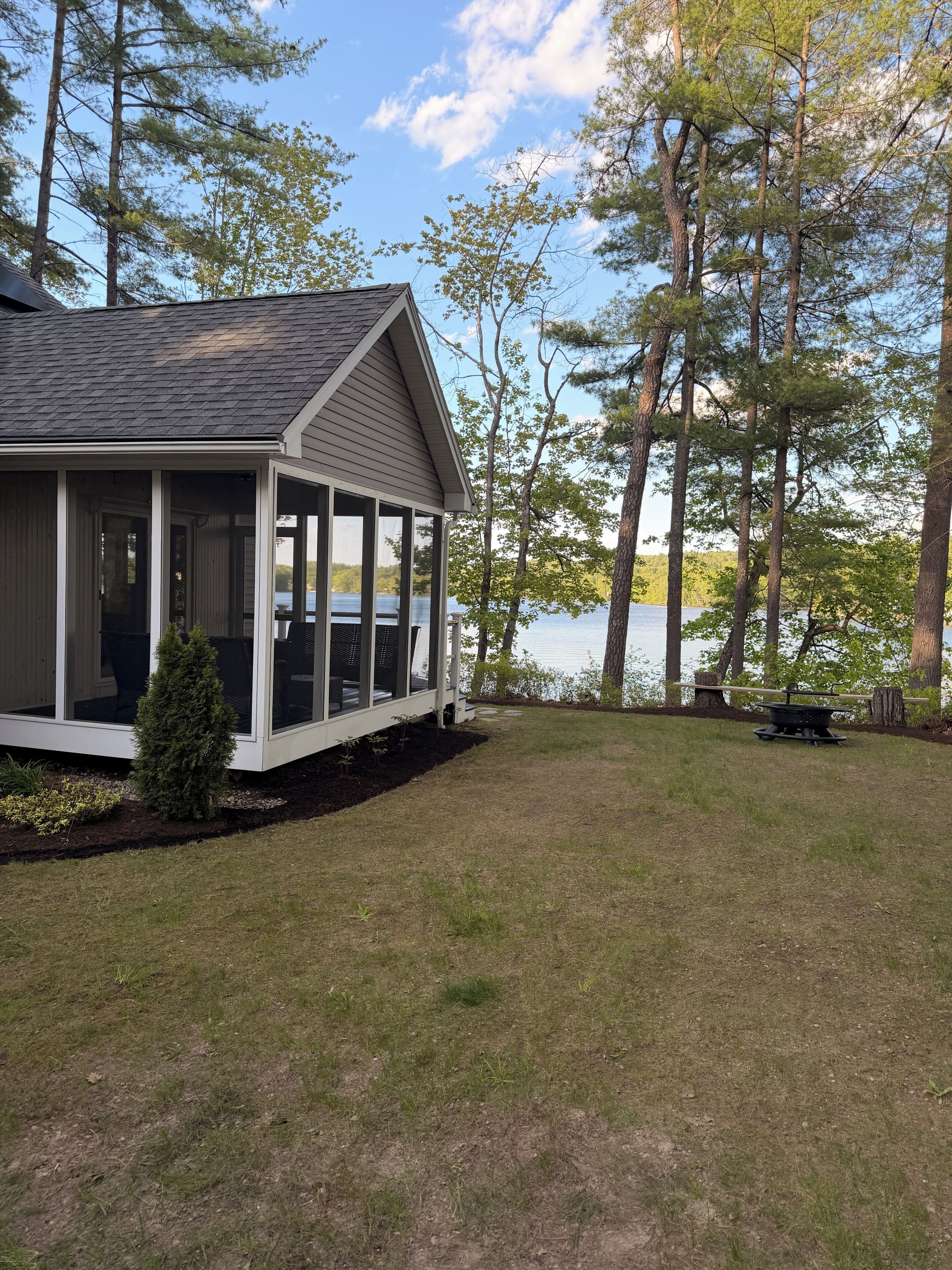 A house with a covered porch, a small lawn, and a lake in the background.