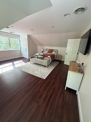 A bedroom with a bed, a nightstand, a TV, and a window.
