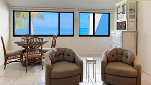 Une pièce avec vue sur la mer, une table à manger avec des chaises et un buffet contenant de la verrerie.