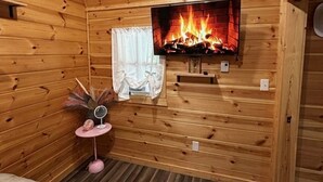 A wooden room with a fireplace, a bed, and a small table with a mirror. - Pink Saddle in Indianapolis (Indianapolis)