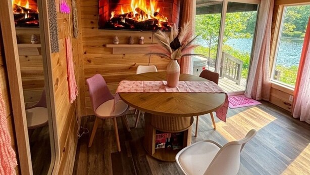 A wooden cabin interior with a fireplace, a dining table, and chairs. - Pink Saddle in Indianapolis (Indianapolis)