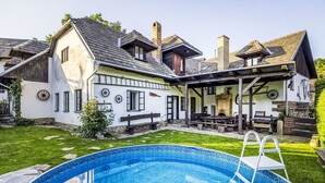 Una casa con piscina, un patio cubierto y una chimenea de piedra.