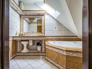 Une salle de bain avec une grande baignoire, un lavabo, un miroir et des toilettes.