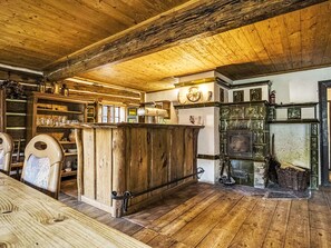 A rustic interior with a wooden bar, shelves with glassware, and a fireplace.