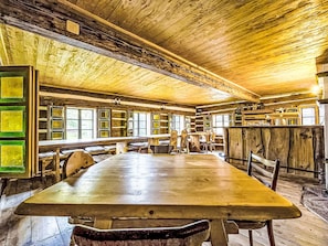 Um interior rústico de madeira com uma mesa grande, bancos e teto alto.
