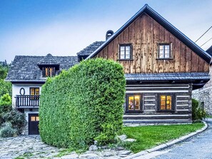 A wooden chalet with a stone facade, a balcony, and a well-maintained garden.