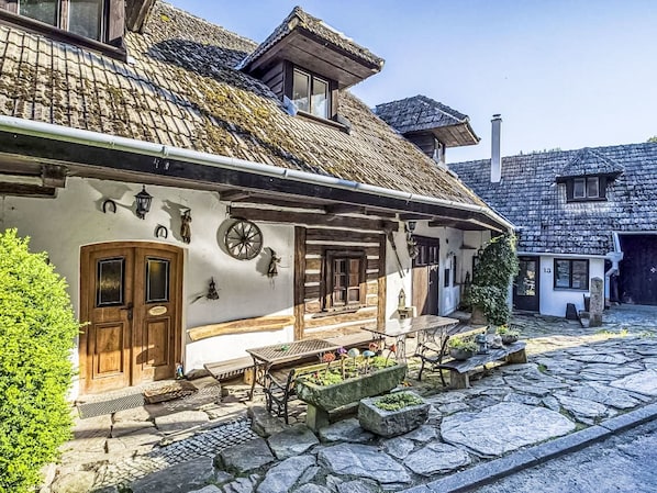 A traditional stone building with a wooden door, a bench, and a small garden area.