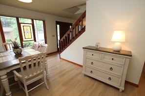 A dining area with a wooden table and chairs, a white dresser with drawers, and a staircase leading to another room. - 1 Silver Ln- NEW LISTING!!- Escape to the perfect beach retreat, ideally located on the tranquil shores of Silver Lake. (Rehoboth Beach)