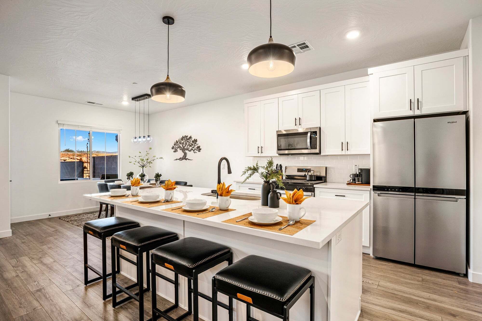 A modern kitchen with white cabinets, a stainless steel refrigerator, and a central island with bar stools.