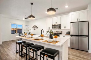 A modern kitchen with white cabinets, a stainless steel refrigerator, and a central island with bar stools. - Juniper House at Skyline, Private Spa (Washington)