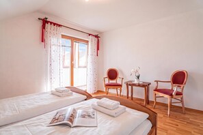 A hotel room with two beds, a small table, two chairs, and a window with curtains. - Logar Farm Stay near Lake Cerknica - R5, Grahovo, Slovenia (Grahovo)