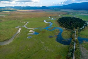 Vista aérea de un río serpenteando por un paisaje con zona boscosa y montañas distantes.