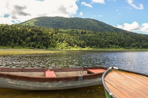 Un bote de madera amarrado en un lago tranquilo con una colina boscosa al fondo.
