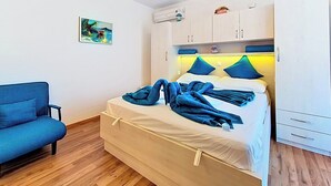 Ein Schlafzimmer mit einem Bett, einem blauen Sofa, einem Gemälde, einer Klimaanlage und einem Kleiderschrank.