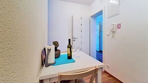 Ein schmaler Flur mit gedecktem Tisch für zwei Personen, einer Weinflasche und einem Glas.
