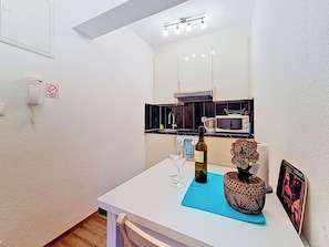 A small kitchenette with a microwave, a sink, and a stove. There is a bottle of wine and a vase with flowers on the counter. - Apartment Palma by Interhome (Stanići)