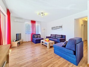 A modern living room with a flat-screen TV, a sofa, a coffee table, and a red curtain. - Apartment Palma by Interhome (Stanići)