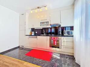 A modern kitchen with white cabinets, a microwave, a coffee maker, and a red rug. - Apartment Palma by Interhome (Stanići)