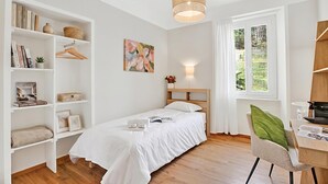 Una camera da letto con un letto, una scrivania, una sedia, una libreria, una finestra e un quadro.