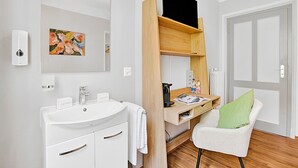 Un bagno moderno con lavandino bianco, specchio e mobile contenitore in legno.