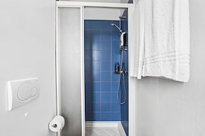 Une salle de bain avec une douche, des toilettes et un porte-serviettes.