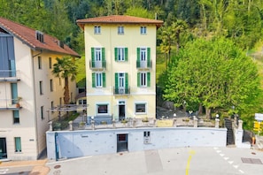 Un edificio de varios pisos con balcones, un letrero que dice 'Villa Lygia' y una exuberante colina verde circundante.