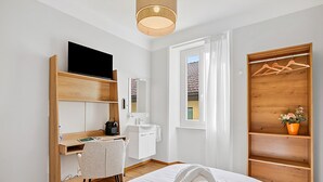 A hotel room with a bed, a desk, a chair, a TV, a wardrobe, and a window. - Agra 6 (Lugano), single, Shared Bathroom, Agra -Lugano, Switzerland (Agra -Lugano)