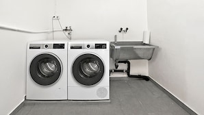 A laundry area with two front-loading washing machines and a metal sink. - Agra 6 (Lugano), single, Shared Bathroom, Agra -Lugano, Switzerland (Agra -Lugano)