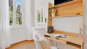 A modern bathroom with a sink, mirror, and a wooden shelf with a plant. - Agra 5 (Lugano), single, Shared Bathroom, Agra -Lugano, Switzerland (Agra -Lugano)