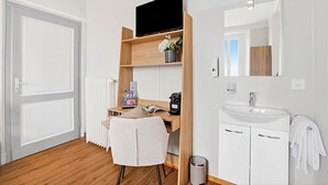Ein Hotelzimmer mit einem Holztisch, einem Fernseher, einem Waschbecken und einem Spiegel.