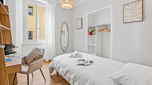 Een slaapkamer met een bed, een stoel, een bureau, een kledingkast en een hanglamp.