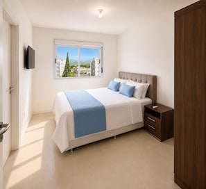 Ein Schlafzimmer mit Bett, Nachttisch und einem Fenster mit Blick auf Gebäude und Bäume.