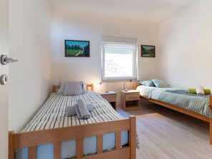 Ein Schlafzimmer mit zwei Betten, einem Fenster und zwei Bildern an der Wand.