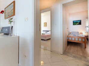 A hotel room with a bed, bedside table, lamp, and a painting on the wall.
